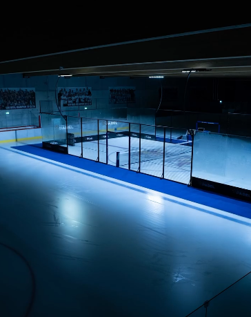 Piste de padel éclairée en bleu installée au centre d’une patinoire sombre à Salzbourg