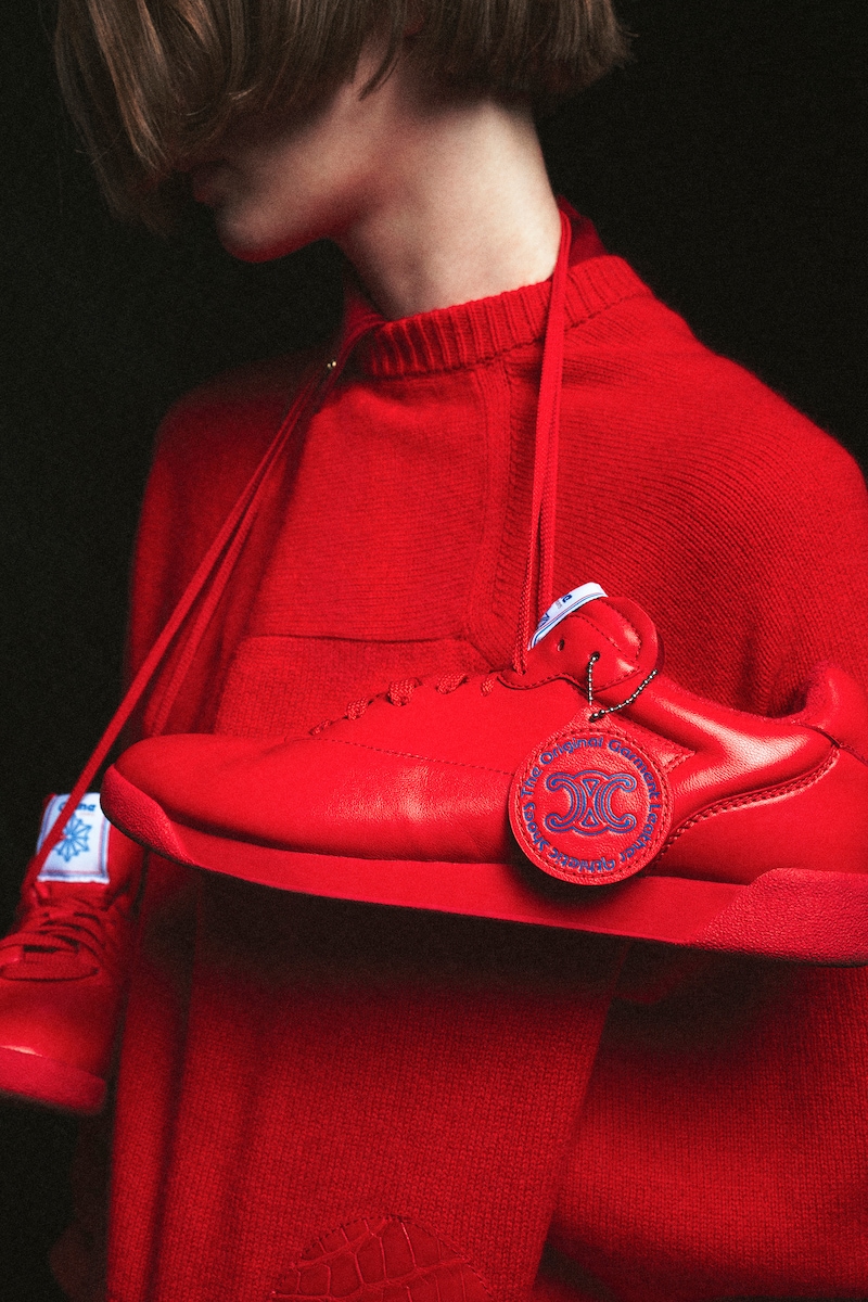 Mannequin vêtue de rouge tenant une Celine Reebok Freestyle Lo rouge devant son visage